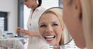 Woman with dental veneers smiles in mirror