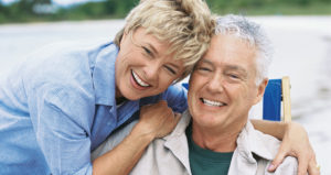 Older couple cuddles together smiling and free of periodontal disease