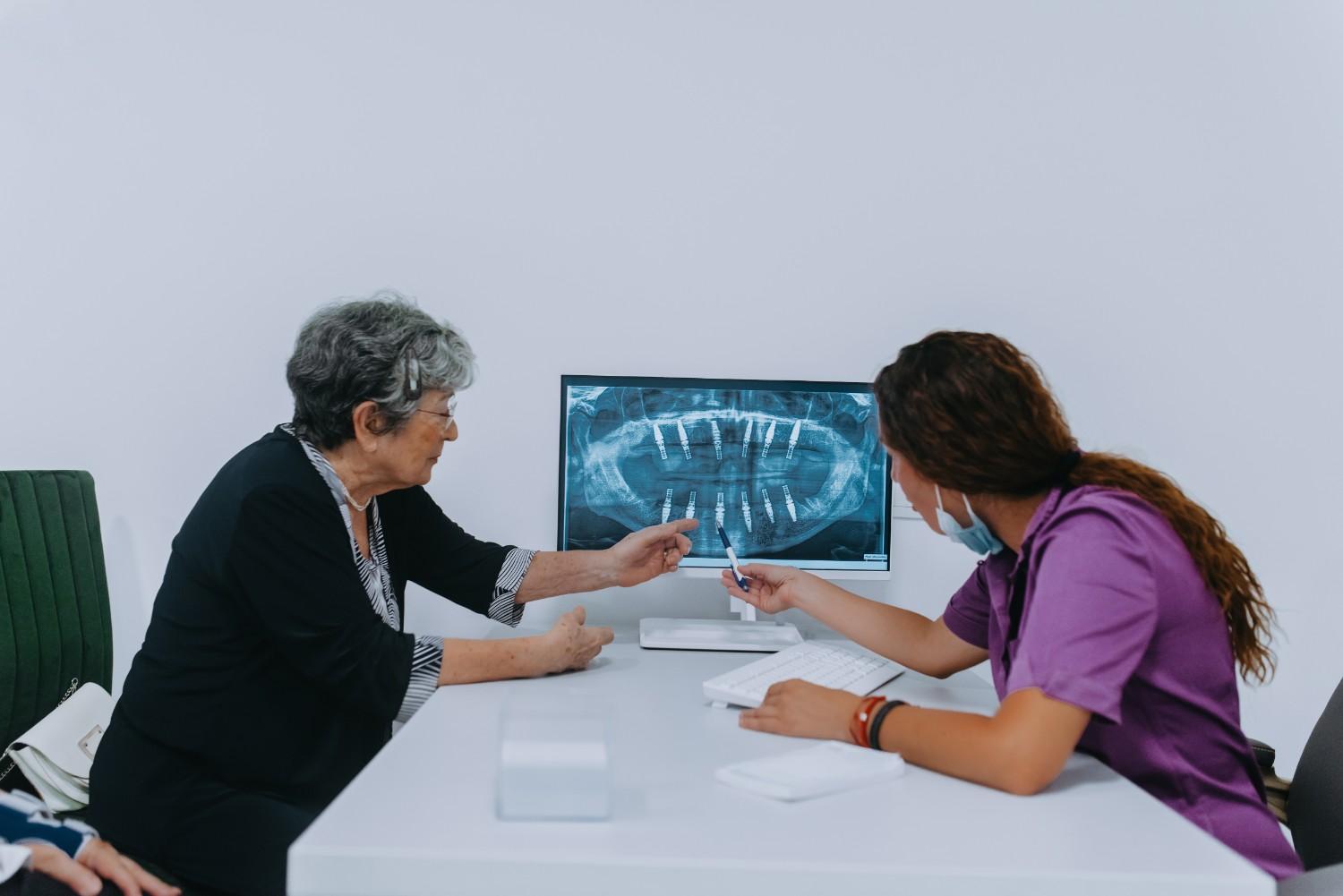 Dentist discussing a dental X-ray with an older patient in an office.