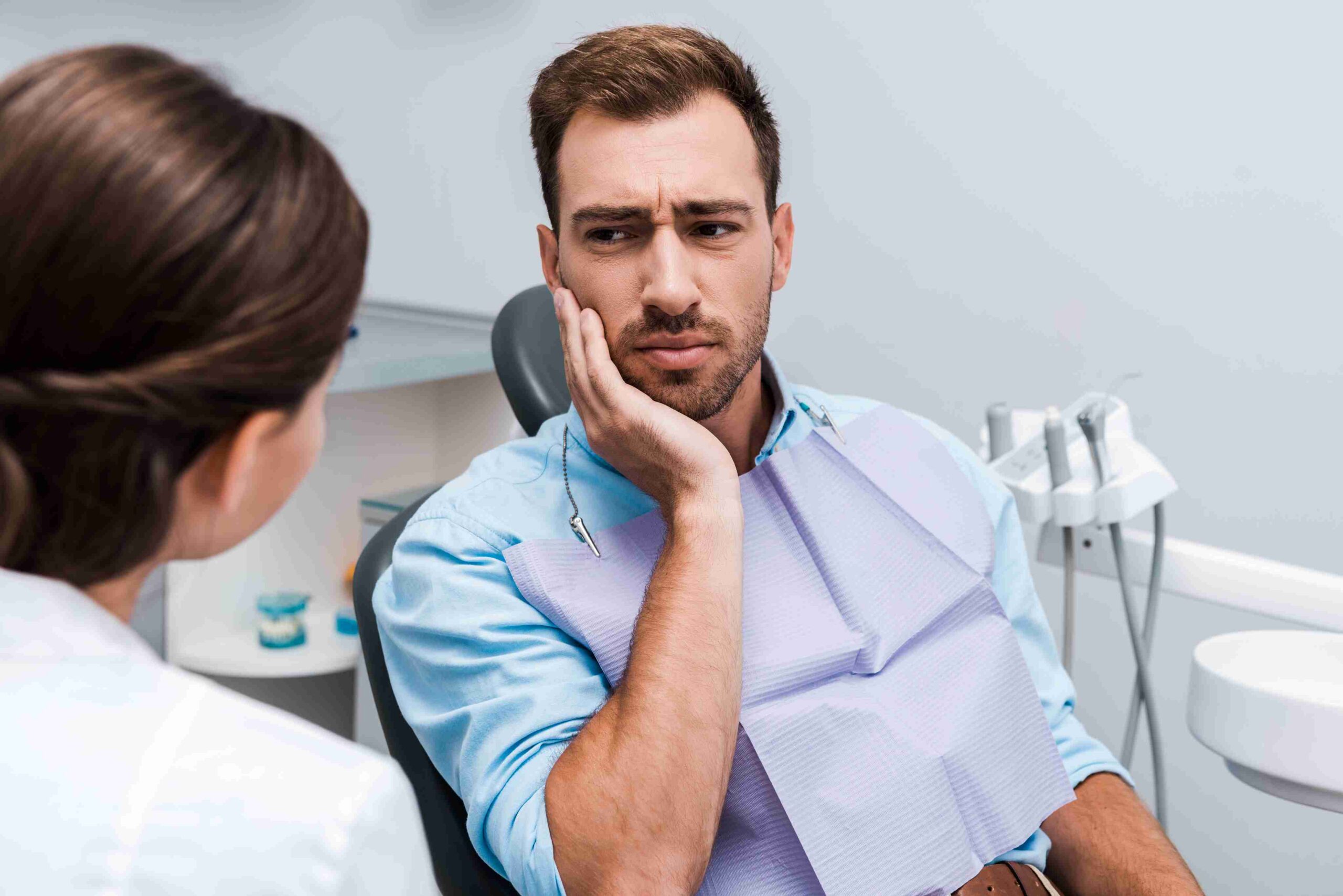 Patient with a toothache speaking to a dentist.