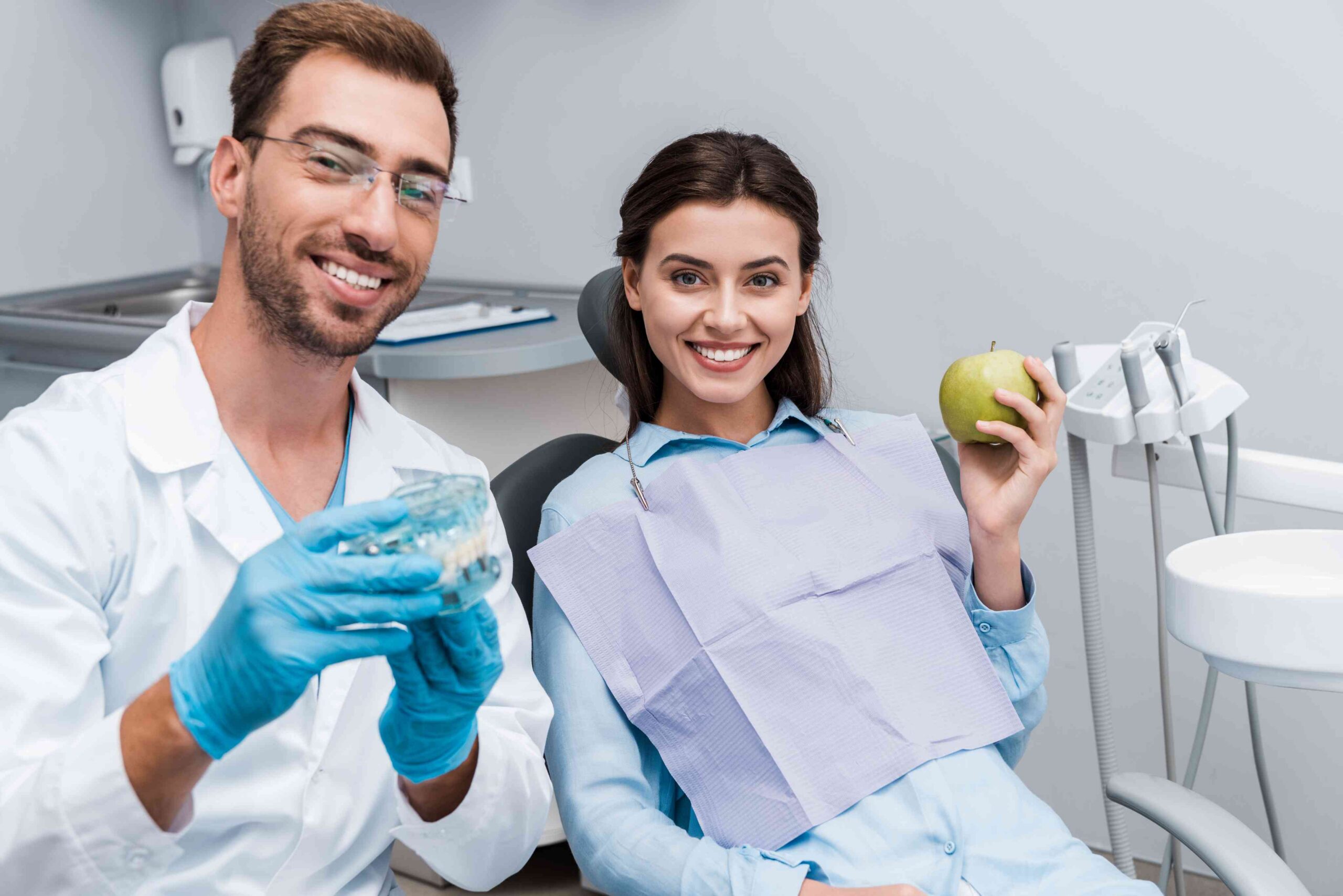 Dentist explaining dental implants while patient holds a healthy apple.
